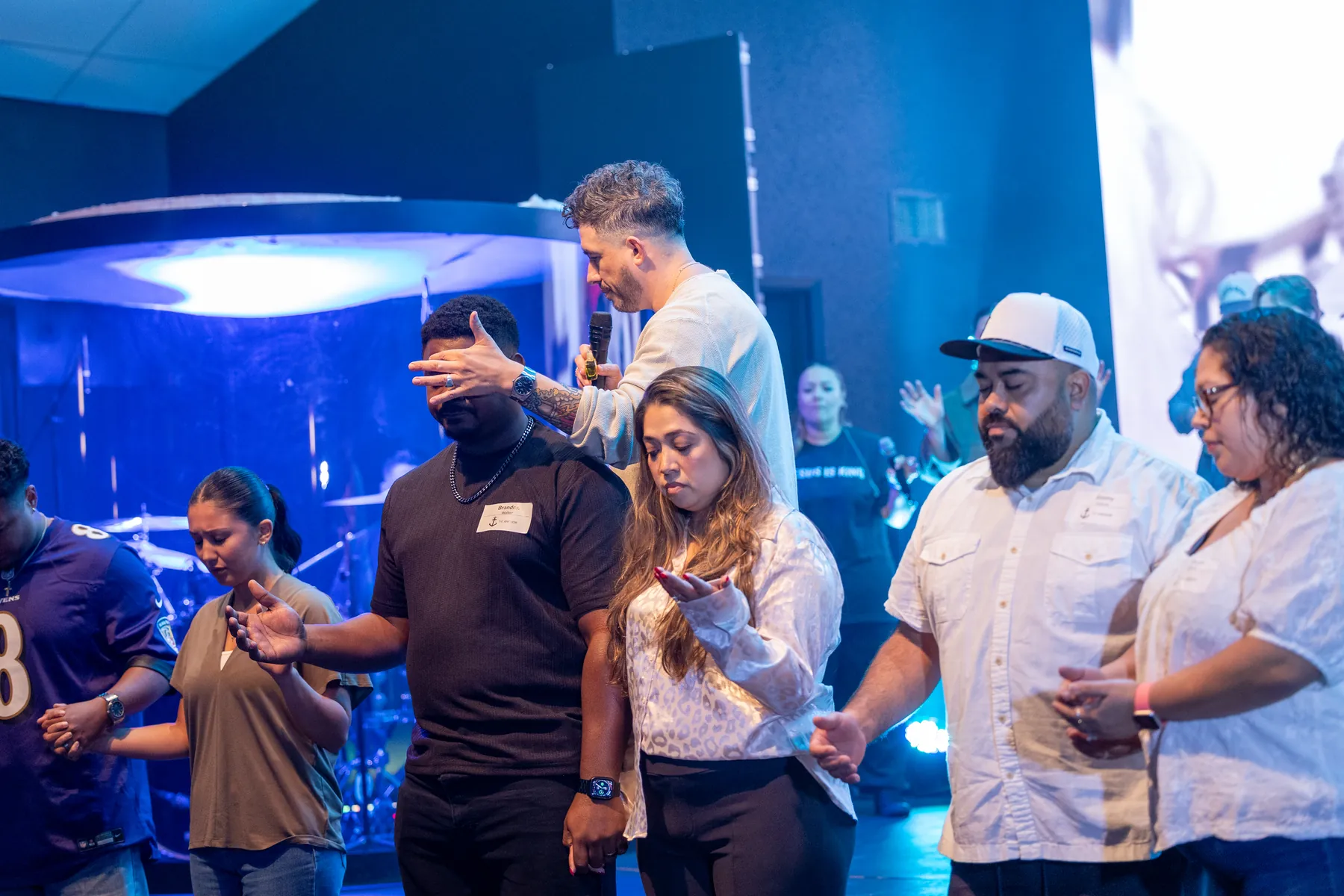 Pastor Rafael praying over new leaders on stage